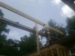 Carpenter setting a ridge beam over a new addition frame — Ice Dam Removal by Roofing Brothers in Bridge City