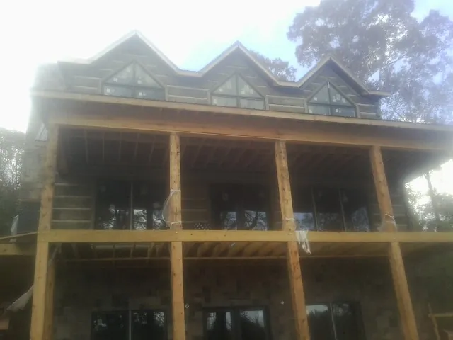 Dormers and porch framing on a large log home under construction — Roof Coating work by our crew in Bridge City