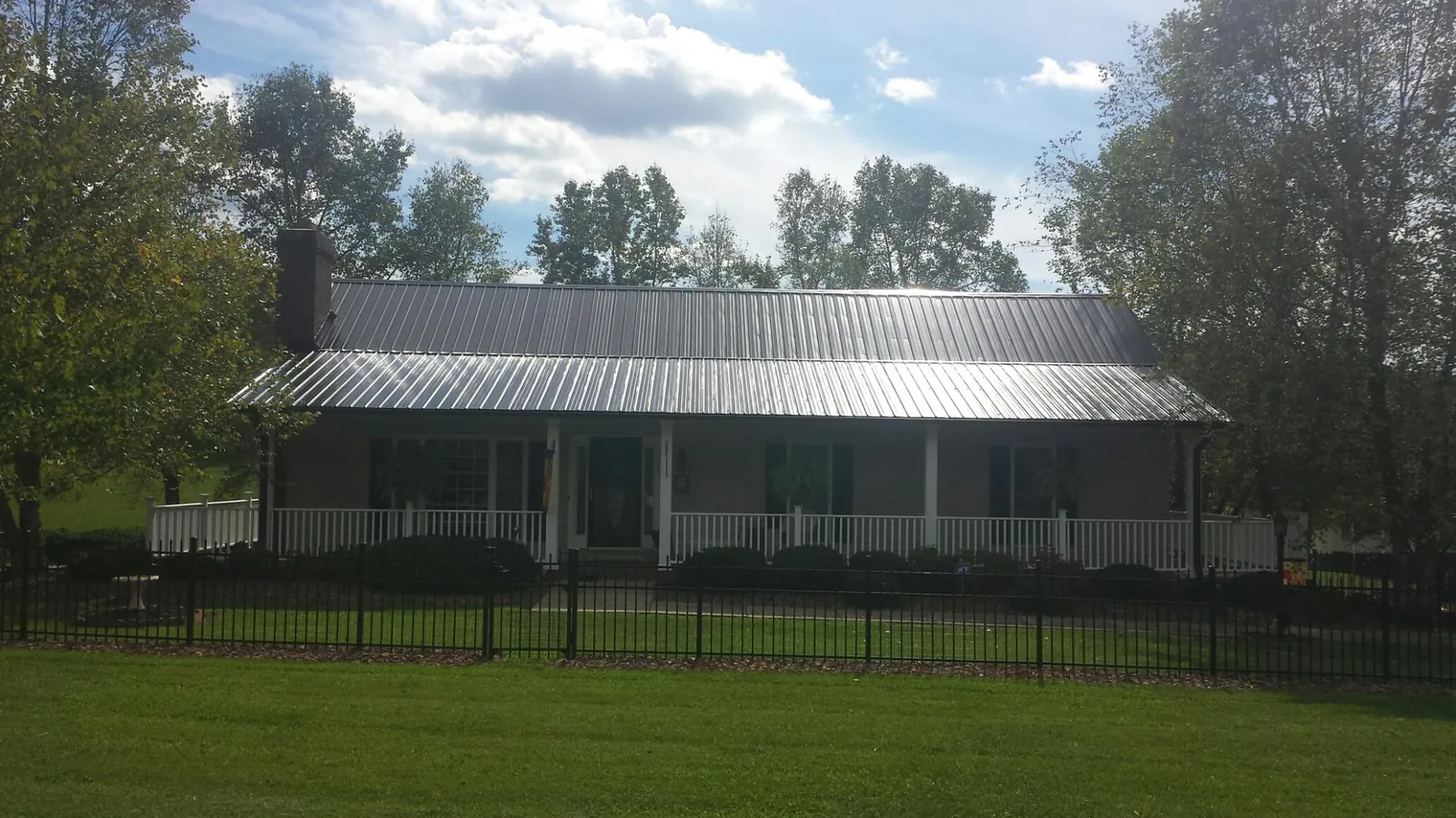 Gray metal roof on a brick ranch with a full width front porch — Gutter Guard Installation work by our crew in Bridge City