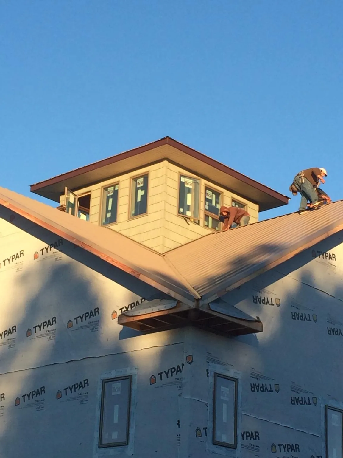 Roofers working around a rooftop cupola on a new metal roof at sunset — Roof Waterproofing in Bridge City by Roofing Brothers